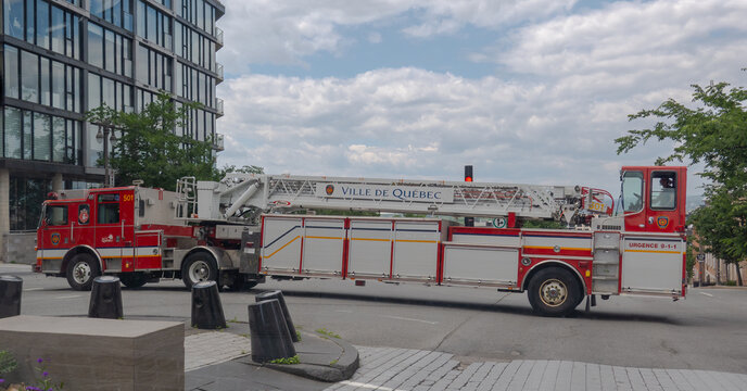 Quebec City, Quebec, Canada. July 27, 2026. Side view of Ville de Quebec fire truck with extended ladder driving on urban street.