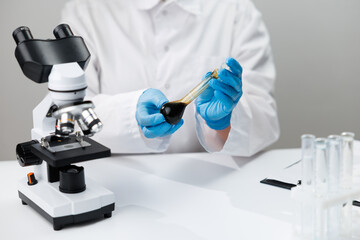 Fototapeta premium Laboratory oil analysis with technician holding dark oil sample for viscosity testing and research background for report design