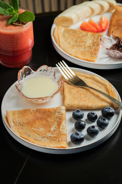 Pancakes with blueberry and honey on a white plate