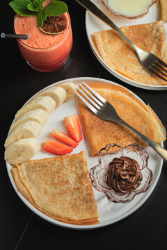 A plate of crepes filled with chocolate spread and topped with banana slices and mint