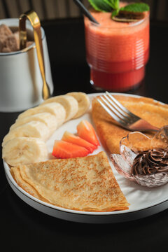 A plate of crepes filled with chocolate spread and topped with banana slices and mint