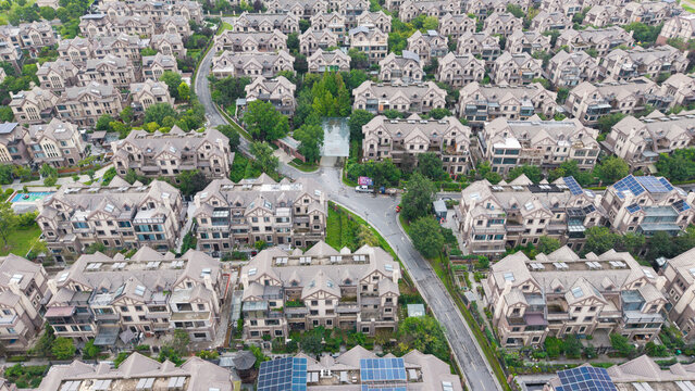 Aerial wide view of dense villa residential community beside lake with lush green trees