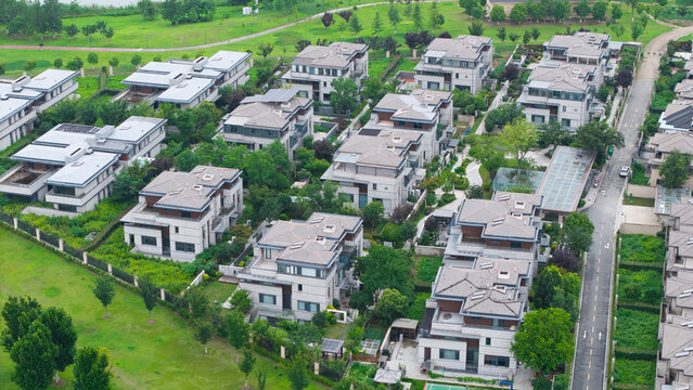 Aerial wide view of dense villa residential community beside lake with lush green trees