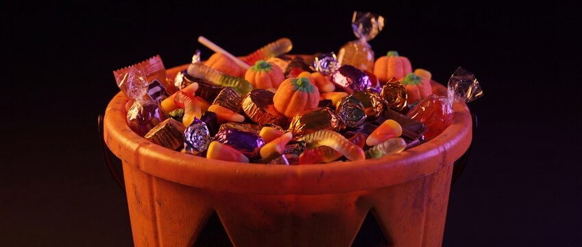 Halloween candy bucket filled with assorted treats on a black background
