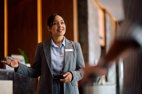 Happy hotel manager greeting arriving guest in lobby.