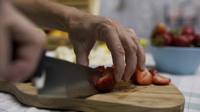 Sharp knife cutting through beautiful strawberry on cutting board in slow motion