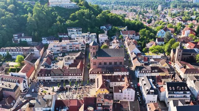 Malerische Ansicht von Homburg an der Saar mit der markanten Stadtkirche, dichten gr&uuml;nen B&auml;umen im Vordergrund und dem bewaldeten Schlossberg unter blauem Sommerhimmel.