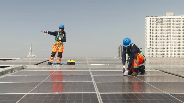 Two solar technicians inspecting rooftop photovoltaic panels, one adjusting panel alignment while colleague points and checks installation details.