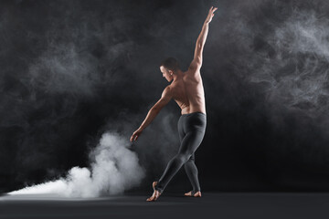 Professional dancer practicing moves on black background with smoke, back view © New Africa