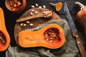 Naklejka na ściany i meble Top view of raw butternut squash with wooden spoon and seeds on wooden cutting board. Halfs of pumpkin close up. Food photography