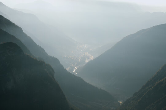 Morning mist fills the valley surrounding Cortina d'Ampezzo beneath layered mountain ridges. Atmospheric Dolomite landscape with soft light and alpine scenery