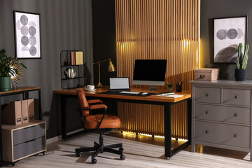 Fototapeta premium Stylish workplace with wooden desk, computer, laptop and comfortable chair in office