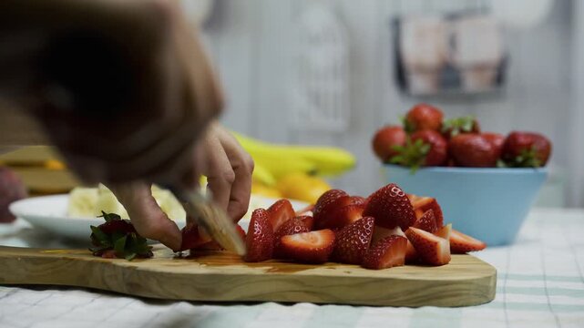 Closeup tracking shot of chef cutting strawberries on board