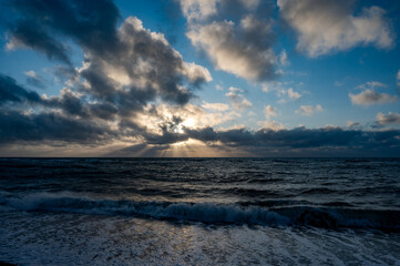 Obraz premium Dramatic Sunbeams Piercing Storm Clouds Over the North Sea