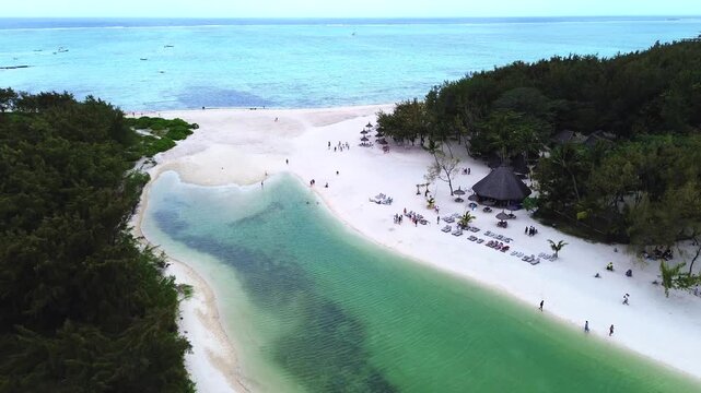 Aerial view capturing the iconic coastal layout of Ile aux Cerfs (Deer Island), Mauritius. Winding turquoise lagoon channel with clear shallow water, bordered by an expansive white sand beach featurin