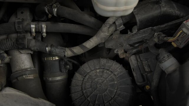 Car engine inspection under the hood in a garage on a sunny day