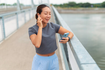 Fototapeta premium Woman listening to music on smartphone using earbuds outdoors