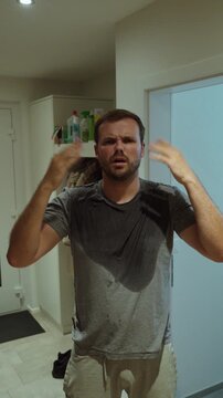 Overheated man fanning himself during extreme heatwave indoors