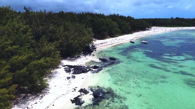 Aerial view capturing the iconic coastal layout of Ile aux Cerfs (Deer Island), Mauritius. Winding turquoise lagoon channel with clear shallow water, bordered by an expansive white sand beach featurin