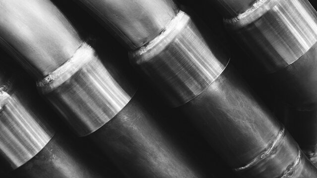 Close-up of black metal pipes with welded joints, part of an industrial machine; pipes are tightly packed and aligned. tech industrial technology background