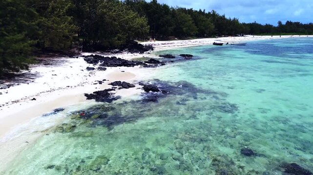 Aerial view capturing the iconic coastal layout of Ile aux Cerfs (Deer Island), Mauritius. Winding turquoise lagoon channel with clear shallow water, bordered by an expansive white sand beach featurin