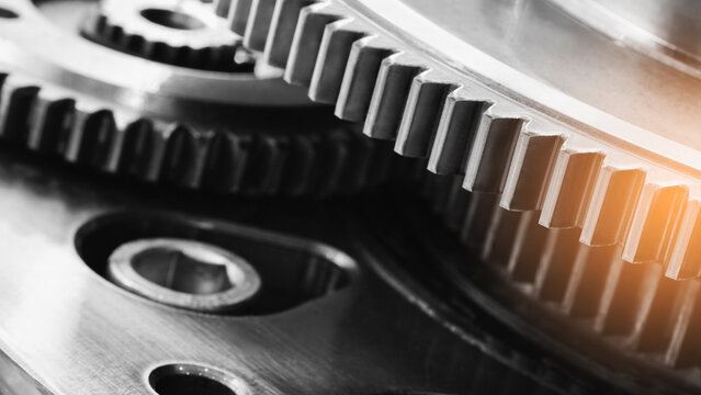 close-up interlocking metal gears. teeth and their precise alignment are visible. Shiny metal surfaces reflect light. Industrial mechanical parts are shown. tech industrial technology background