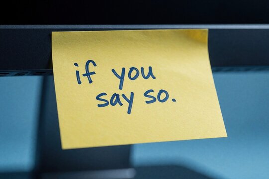 Yellow sticky note with handwritten text if you say so attached to computer monitor. Memo implies doubt, agreement, or resignation in communication.