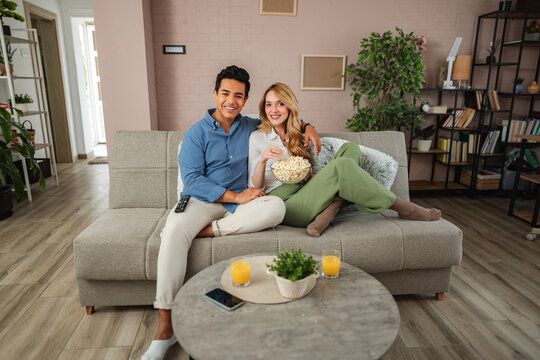 Happy couple relaxing on sofa enjoying movie night at home