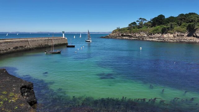 DOUARNENEZ, FRANCE &ndash; July 4, 2026: Turquoise harbor water with anchored sailboats and a stone breakwater in Douarnenez, Brittany, France. Sunny summer view of a peaceful marina on the Atlantic coast.