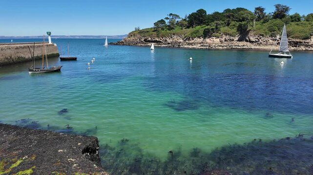DOUARNENEZ, FRANCE &ndash; July 4, 2026: Stone breakwater protecting a turquoise harbor with anchored sailboats in Douarnenez, Brittany, France. Bright summer day on the Atlantic coast with calm water and a