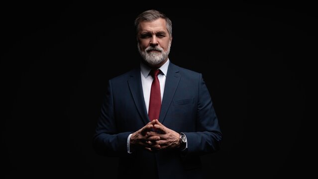 Studio portrait of senior businessman in suit on dark background
