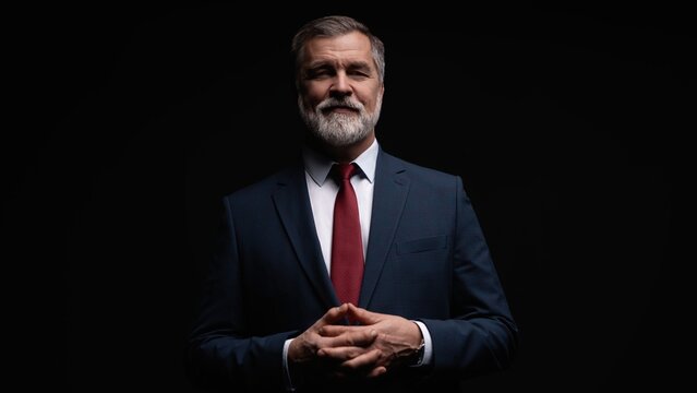 Studio portrait of senior businessman in suit on dark background