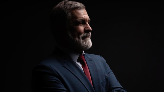 Studio portrait of senior businessman in suit on dark background