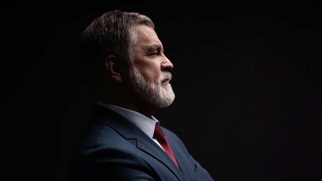 Studio portrait of senior businessman in suit on dark background