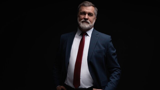 Studio portrait of senior businessman in suit on dark background