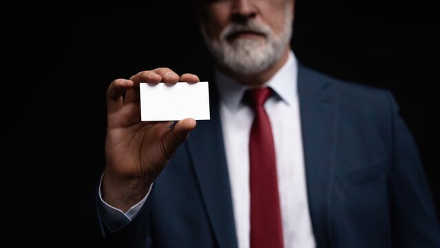 Mature businessman in suit holding office business card advertisement.
