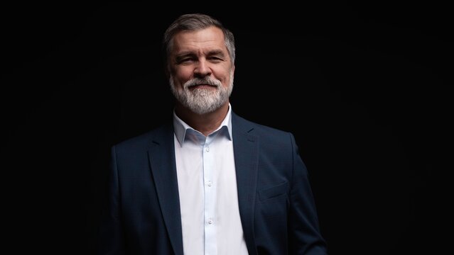 Studio portrait of senior businessman in suit on dark background