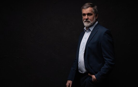 Studio portrait of senior businessman in suit on dark background