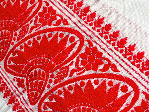 Close-up of a traditional Assamese Gamosa fabric texture featuring iconic red and white woven patterns.