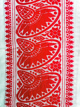 Close-up of a traditional Assamese Gamosa fabric texture featuring iconic red and white woven patterns.