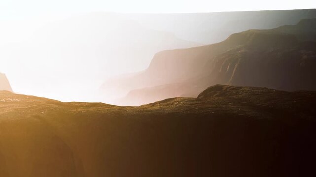 The sun sets over a mountain range, creating shadows and light effects. The terrain is rocky and rugged. The scene captures the beauty of nature at twilight.