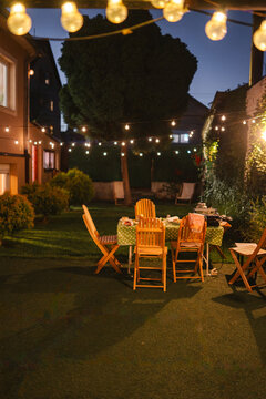 Backyard garden party setup with illuminated string lights at night