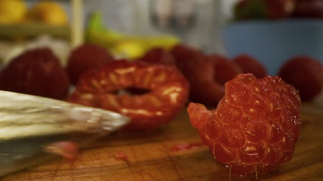 Small knife cutting through tiny raspberry - extreme closeup shot