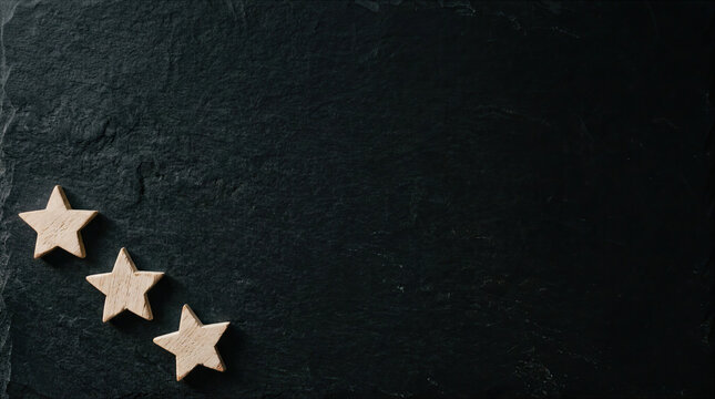 Three wooden stars on dark textured slate background with copy space for rating, quality, and feedback concepts