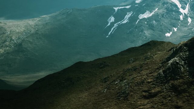 Mountains are visible with a gray and cloudy sky. One side shows snow covered peaks. The other side displays dark and rocky slopes. The landscape has a vast open space in the background.