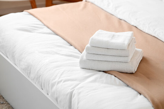 Stack of clean white towels on a hotel bed with fresh linens, Hospitality and comfort