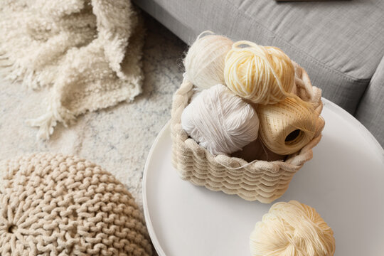 Basket with knitting yarn on table in living room, top view
