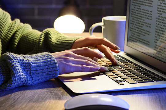 Female writers hands editing text on laptop before publishing in office at night, closeup