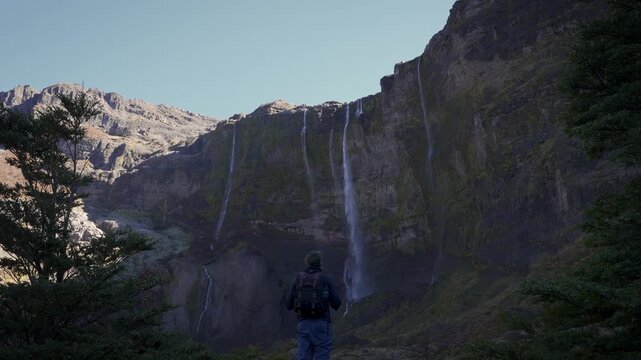 Hiker with a backpack trekking through a natural trail towards the Casta&ntilde;o Overa glacier and waterfalls in Nahuel Huapi National Park, Argentina.