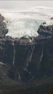 Casta&ntilde;o Overa glacier and cascading waterfalls flowing down a rocky cliff in Nahuel Huapi National Park, Argentina, showcasing glacial ice and mountain water.